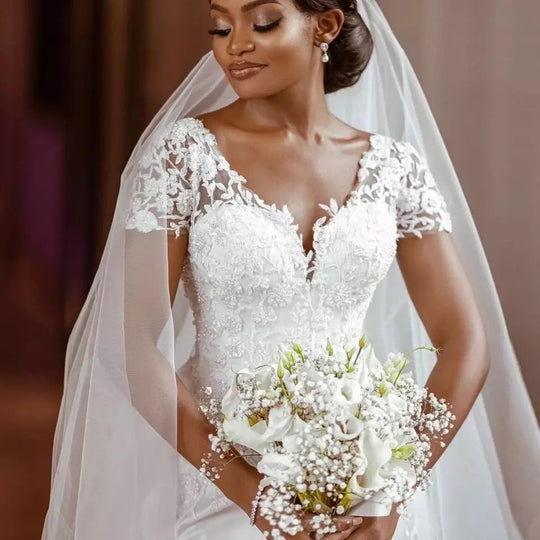 Bridal wedding gowns featuring a beautiful bride in a lace detailed dress holding a bouquet.